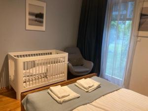 ein Schlafzimmer mit einem Kinderbett mit einem Stuhl und einem Stuhl in der Unterkunft WILANOWSKA apartment & garden in Warschau