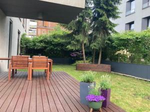 eine Holzterrasse mit einem Holztisch und einer Bank in der Unterkunft WILANOWSKA apartment & garden in Warschau