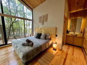 ein Schlafzimmer mit einem Bett und einem großen Fenster in der Unterkunft Casa Nórdica en el Bosque in Cerro Gordo