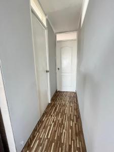 un corridoio vuoto con porta bianca e pavimento in legno di Apartamento Con Estilo A 4 Min Del Aeropuerto-6 Piso! a Lima