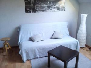 a white bed in a room with a table and a vase at Gîte du vigneron in Mittelwihr