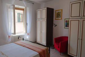 um quarto com uma cama e uma cadeira vermelha em Appartamento La Valle em Passignano sul Trasimeno