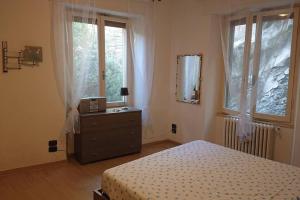 um quarto com uma cama, uma cómoda e janelas em Appartamento La Valle em Passignano sul Trasimeno