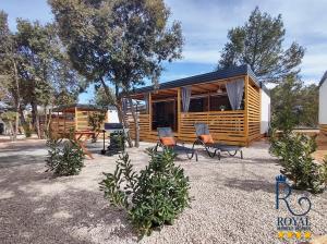 una cabaña con sillas y mesas en un patio en Royal R mobile homes, kamp Soline, Biograd en Biograd na Moru