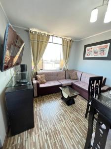 un soggiorno con divano e TV di Apartamento Con Estilo A 4 Min Del Aeropuerto-6 Piso! a Lima