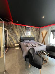 a bedroom with a large bed and a red accent wall at spa de la quarterelle LOVE ROOM 88 VOSGES in Remiremont