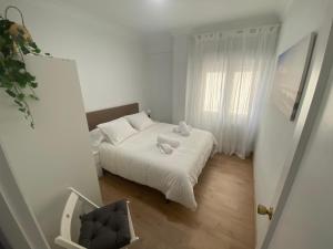 a small white bedroom with a bed and a window at Pleno centro, cerca de todo con wifi gratis y ascensor in Santander