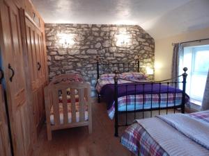 a bedroom with two bunk beds and a stone wall at Burry Farm Cottage in Swansea