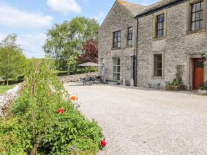 a stone house with a patio and flowers in front of it at The Dairy in Carnforth