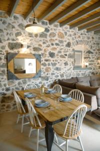 a wooden table and chairs in a room with a stone wall at Villa Calliope in Kalymnos