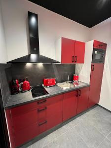 a red kitchen with a stove and a sink at spa de la quarterelle LOVE ROOM 88 VOSGES in Remiremont
