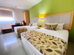 a hotel room with two beds and green walls at Sleep Inn Culiacan in Culiacán