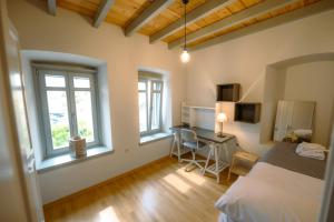 a bedroom with a bed and a desk and two windows at Villa Calliope in Kalymnos