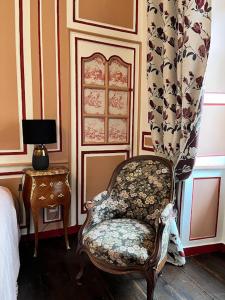 ein Schlafzimmer mit einem Stuhl und einem Tisch mit einer Lampe in der Unterkunft La tour cachée in Mortain