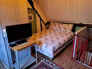 um quarto com uma cama e uma secretária com um monitor de computador em Chez Robins em Trie-Château
