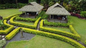 a resort with two huts in a garden at JJ's Retreat in Rarotonga