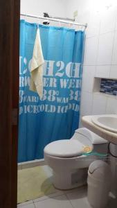 a bathroom with a toilet and a blue shower curtain at Posada Villa Mayo Habitación Matrimonial Equipada in Loma de Guerra