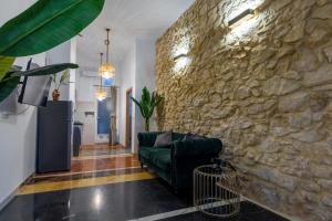sala de estar con pared de piedra y sofá verde en Casa Alicantina, en Alicante