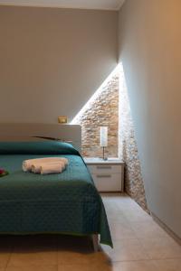 una camera con un letto verde e una parete in pietra di B&B al Vico Pepe a Castelmezzano