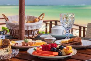 une table avec des assiettes de nourriture et une corbeille de fruits dans l'établissement Árvo Boutique Hotel, à Maragogi