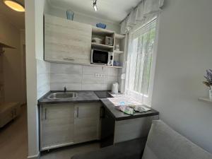 a small kitchen with a sink and a microwave at Mira apartman in Zamárdi