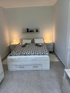 a bedroom with a white bed with two lamps on it at Mira apartman in Zamárdi