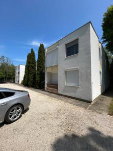 una casa gris con un coche aparcado delante de ella en Mira apartman, en Zamárdi