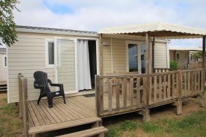 a chair sitting on a deck with a gazebo at Mobil home vue mer camping Tohapi in Vias