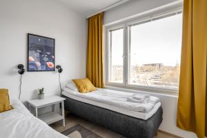two beds in a room with a large window at Hiisi Homes Turku Ratapiha in Turku