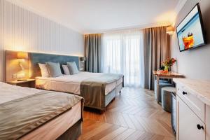 een hotelkamer met 2 bedden en een televisie bij Belmar Park Resort & SPA in Władysławowo