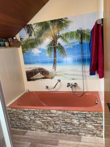La salle de bains est pourvue d'une baignoire et d'une fresque murale de palmiers. dans l'établissement Appartement Biberach, à Biberach an der Riß