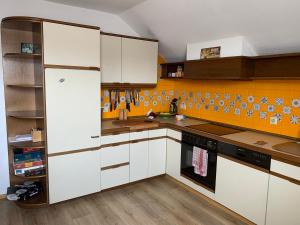 una cocina con armarios blancos y una pared de color naranja en Appartement Biberach, en Biberach an der Riß