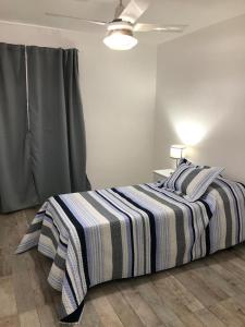 a bedroom with a bed with a striped blanket at Amplio, luminoso y centrico dep. 3 dorm in Concordia