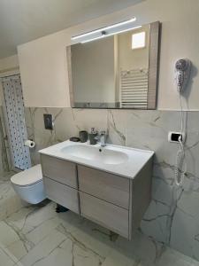 ein Badezimmer mit einem Waschbecken, einem WC und einem Spiegel in der Unterkunft La Mansarda in Stresa