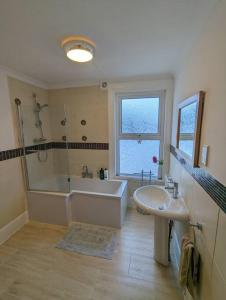a bathroom with a tub and a sink and a bath tub at Spacious first floor family flat, Sea view in Torquay