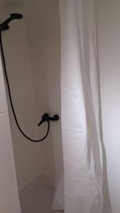 una ducha con una manguera pegada a una pared blanca en L'Essentiel, en Dinant