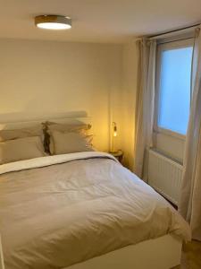a bedroom with a white bed and a window at L'Essentiel in Dinant