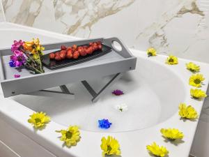 eine Badewanne mit einem Tablett mit Erdbeeren und Blumen in der Unterkunft Comfortable 2 Bedroom Flat In The City Centre in Edinburgh