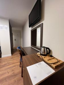 a room with a desk with a television on a wall at Amber Hotel in Sarajevo