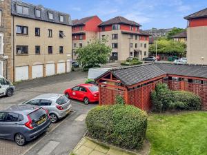 a red building in a parking lot with parked cars at Comfortable 2 Bedroom Flat In The City Centre in Edinburgh