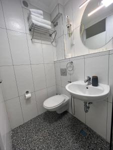 a white bathroom with a toilet and a sink at Amber Hotel in Sarajevo