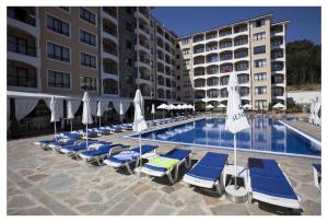 a pool with lounge chairs and umbrellas next to a hotel at Bendita Mare Apartment in Golden Sands
