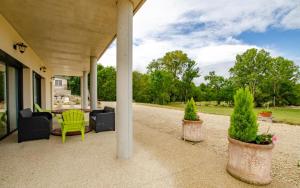 eine Veranda mit zwei Topfpflanzen und einem grünen Stuhl in der Unterkunft Le grand clos in Meurville