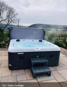 a hot tub sitting on top of a patio at Tyr Ywen Cottage in Abergavenny