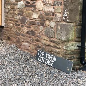 a sign on the ground in front of a brick wall at Tyr Ywen Cottage in Abergavenny