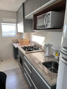 uma cozinha com um lavatório e um fogão forno superior em Apartamento Bauru em Bauru
