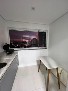 uma cozinha com uma janela, uma mesa e uma cadeira em Apartamento Bauru em Bauru