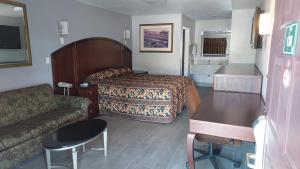 Habitación de hotel con cama y sofá en Regency Inn, en Norco