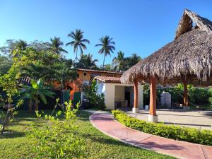 a path leading to a house with a thatch roof at Hotel J.B. in Zihuatanejo