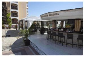 un patio con tavoli, sedie e ombrellone bianco di Bendita Mare Apartment a Golden Sands